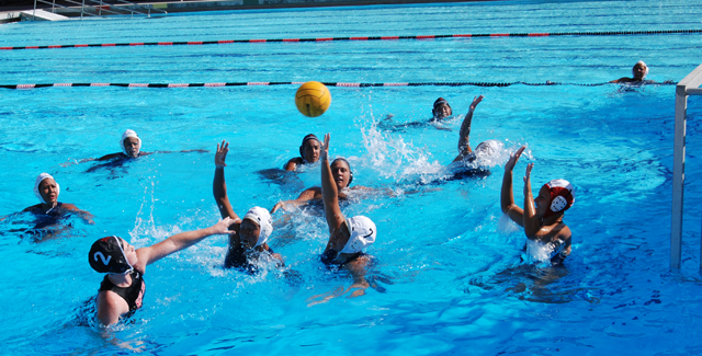 Candice Saylors (#2, left) floats a shot over a pair of Cypress defenders and the goalie for one of her two goals in the Dons OEC match.